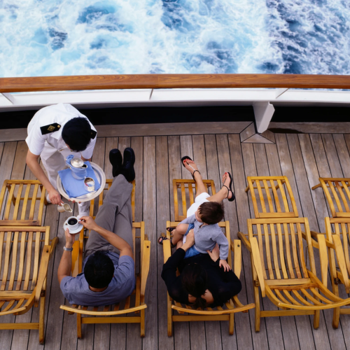 Server_bringing_family_drinks_as_they_lounge_on_cruise_ship_deck._im7Cx2p